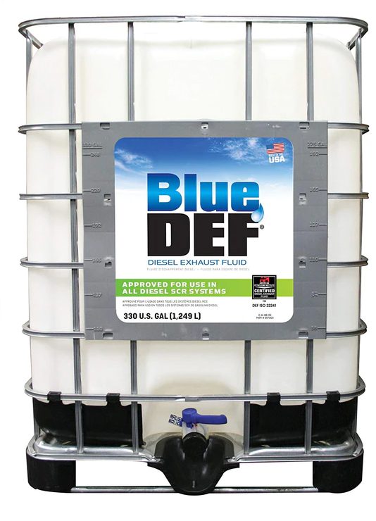 A 330-gallon container of BlueDEF diesel exhaust fluid with a metal frame and a dispensing valve at the bottom.